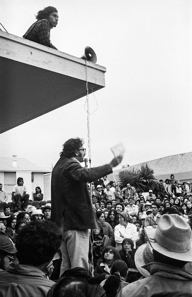 UFW organizer Marshall Ganz addresses farmworkers at a meeting in the yard of the Salinas union office, 1975