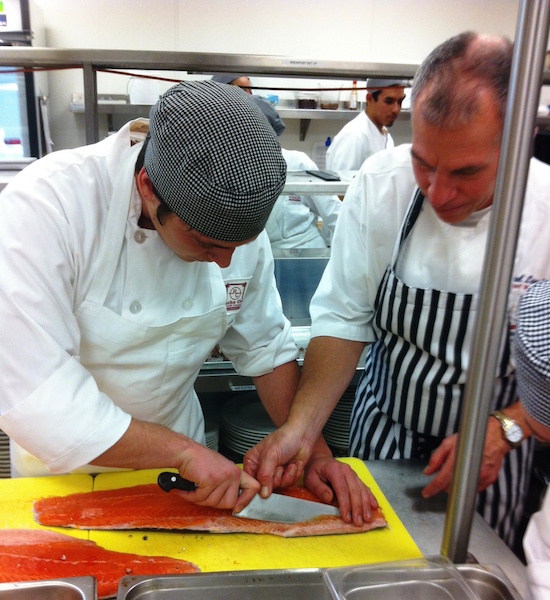 Chef Paul Lee, CEC, instructs student Chase Ewing in manufacturing a salmon