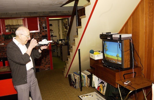 Baer playing a videogame he invented; his basement workshop is in the background. Courtesy of Smithsonian National Museum of American History.