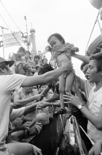 Fellow refugees transfer a Vietnamese child onto a Coast Guard boat in Manila, Philippines on Jan. 8, 1979.