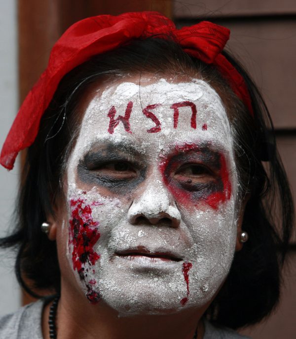 A member of the UDD or Red Shirt puts makeup on her face as a dead person at Lumpini park in Bangkok, Thailand, July 2010. Photo by Apichart Weerawong/Associated Press.