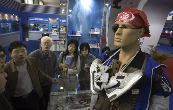 Visitors walk past a mannequin set up to show how individuals attempt to get past customs, smuggling counterfeit products in violation of intellectual property rights law during an exhibition in Beijing, April 17, 2006. Photo by Ng Han Guan/Associated Press.