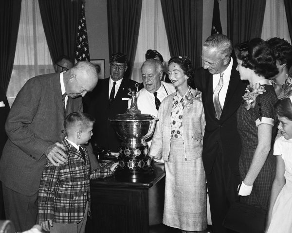 Pres. Dwight D. Eisenhower, left, leans over for a word with 7-year-old Malcom McLean, Jr., as the lad touches the 1959 American Legion Merchant Marine Achievement Award during its presentation at the White House, July 29, 1959. Young Malcolm's father accepted the award on behalf of the Pan American Steamship Corp., which he headed. In the group at right are, from left: Rep. Frank Boykin (D-Ala.), Mrs. McLean, Malcolm McLean, Sr., and Nancy McLean, 13. Photo courtesy of Associated Press.