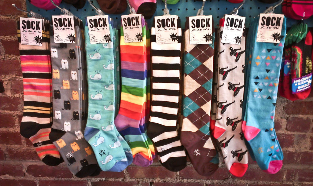 A row of long socks with different patterns and colors, such as a black-and-white striped pair of socks and a rainbow pair.