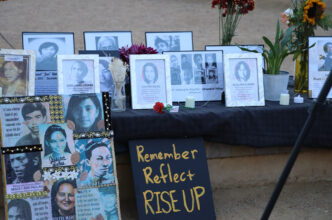 An altar with framed photos of martyrs and heroes who opposed martial law under Ferdinand E. Marcos Sr.’s and similar policies under Rodrigo Duterte. A black sign with golden yellow words "Remember Reflect RISE UP" leans against the table.