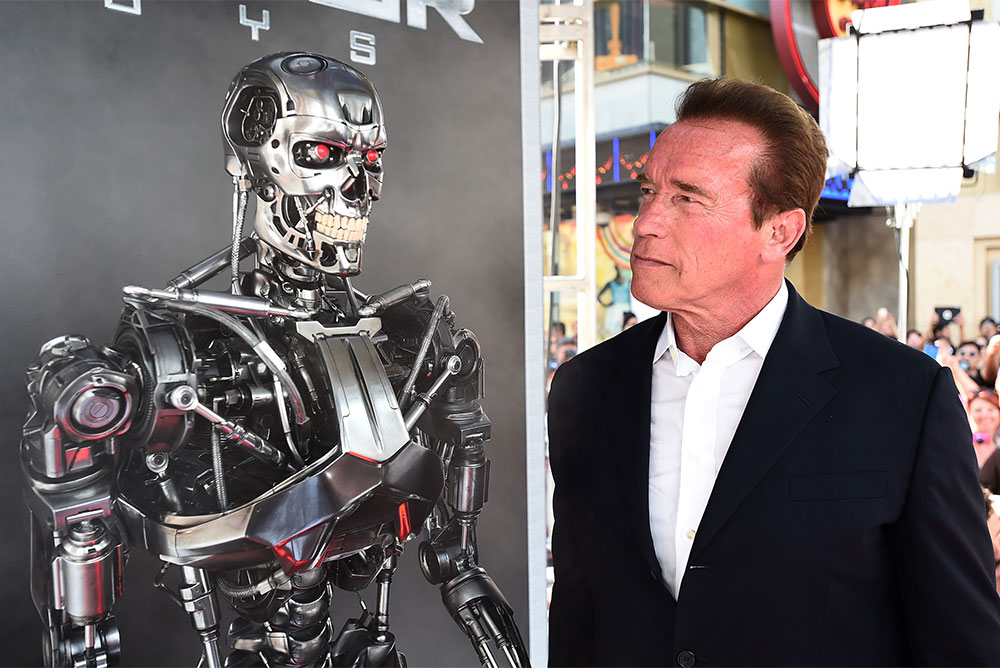 Arnold Schwarzenegger, right, dressed in a suit, stares intensely at a robot, left, from the Terminator movies.