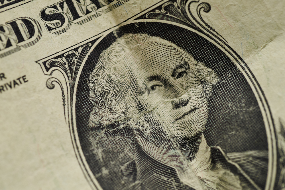 A close up of George Washington on the dollar bill, which is slightly creased.